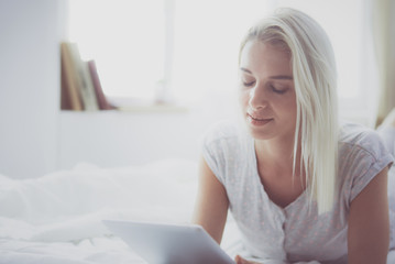 Fototapeta premium Girl holding digital tablet with blank screen and smiling at camera in bedroom