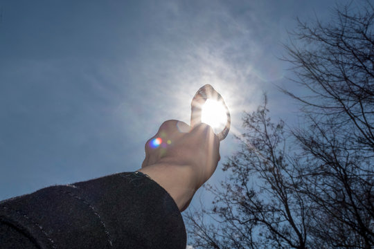 A girl holds rapane in the direction of sunlight.