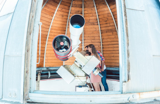 Kids looking through telescope in public star observatory