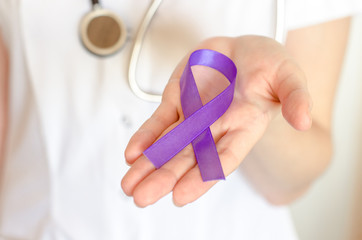 Doctor keeps a purple ribbon as a symbol of epilepsy awareness day close up