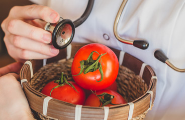 Doctor holds a stethoscope and checks up a tomato concept of control of harvest quality