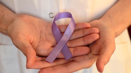 Doctor keeps a purple ribbon as a symbol of epilepsy awareness day around the world close up