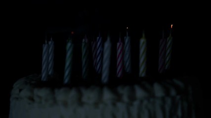 Anniversary cake burning candles in dark