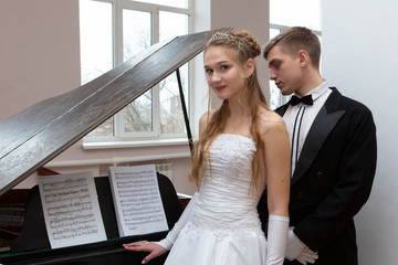 Fototapeta premium Young good looking couple in evening dress and dress coat posing in elegant way in a classical style
