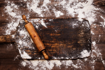Rolling pin and flour on black table. Copy space. Top view