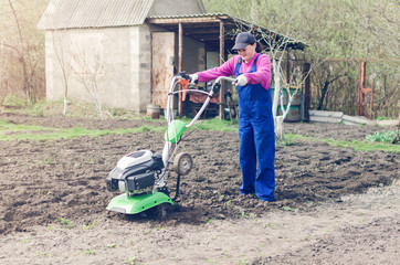 Young girl working in a spring garden with a cultivator
