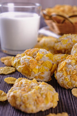 Tasty and beautiful cornflakes cookies and a glass of milk on a wooden table, vertical orientation, closeup