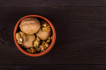 whole walnuts and kernels on wooden background, walnut on a dark old table in a clay pot