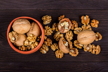 whole walnuts and kernels on wooden background, walnut on a dark old table in a clay pot