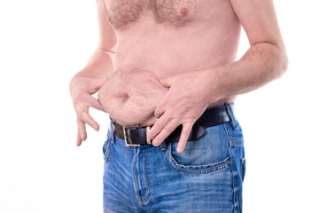 Young topless man touches his fat stomach with two hands islolated on white background - concept getting rid of belly fat, belly button, overweight, diet, lifestyle, health, ugly, weight loss or gain