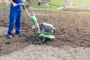 Man working in the spring garden with tiller machine