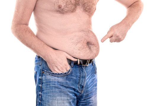 Young topless man points with forefinger to his fat stomach belly button islolated on white background - concept getting rid of belly fat, overweight, diet, lifestyle, health, weight