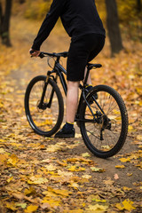 Fototapeta na wymiar Back view of young active man sitting on bicycle and moving along forest path on weekend