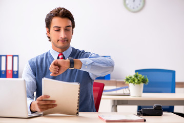 Young handsome employee working in the office 