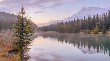 Fototapeta na wymiar Morning mist on the Cascade Pond with beautiful water reflection at Banff National park