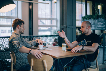 Two young men chatting in a cafe over a cup of coffee