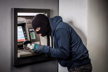 Thief with angle grinder hacks an ATM. Law and crime concept