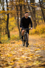 Fototapeta premium Young athlete man riding sports bike on track in autumn park