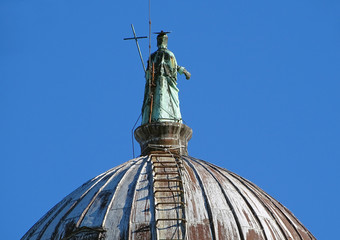 Fototapeta na wymiar Statue of St.John the Baptist on the top of cupola of San Giovanny Baptistery in Pisa, Italy
