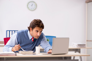 Young handsome employee working in the office 