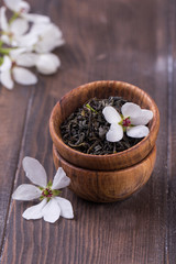 Fototapeta na wymiar wooden bowl with green tea leaves and white flowers.