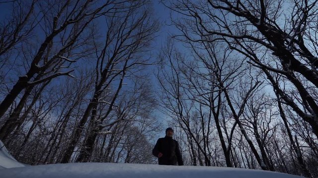Handsome man in a winter jacket and a sweater walks. Beautiful snowy winter day Man make a pace over camera, in the sky