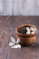 wooden bowl with green tea leaves and white flowers.