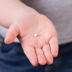 Little girl holding her lost baby tooth.