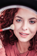 Delighted red haired woman looking at her reflection