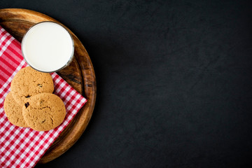 oatmeal cookies with glass of milk on black with copy space