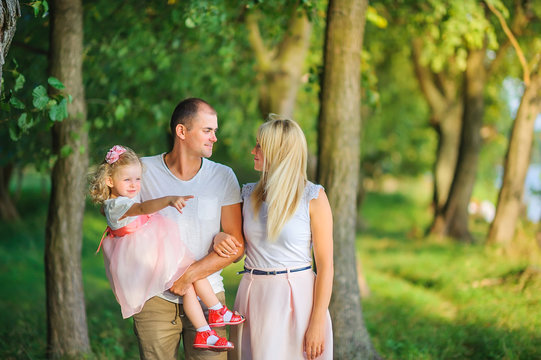 Happy family in a beautiful spring park, dad holds a daughter in his arms, healthy outdoor recreation