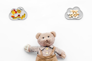 Childhood diseases concept. Treatment of children.Teddy bear toy and pills on white background top view copy space