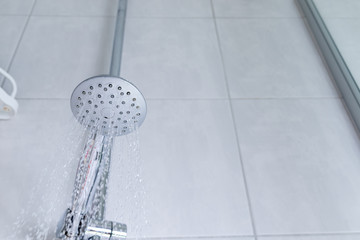 Water falling out of the showerhead in a white bathroom