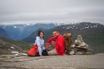 Couple of happy backpack tourist on the top of the mountain neхt to the cairn