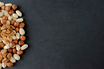 walnuts, hazelnuts, peanuts  on black with copy space. Top view