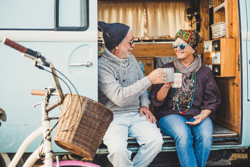 Happy cheerful mature people couple caucasian traceler enjoy and take a break resting sit down out of her van during alternative vacation for nice retired lifestyle together forever with love