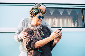 Cheerful old adult couple using technology smart phone internet to take selfie picture for social...