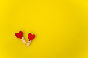 Yellow background with clothespins and red hearts. St. Valentine's Day
