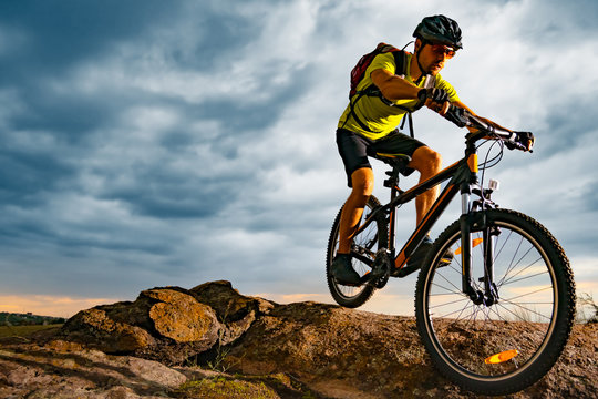 Cyclist Riding the Mountain Bike on Rocky Trail at Sunset. Extreme Sport and Enduro Biking Concept.