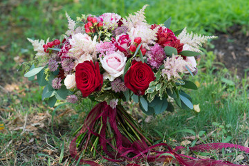 red and pink motley wedding bouquet of fresh flowers and eucalyptus