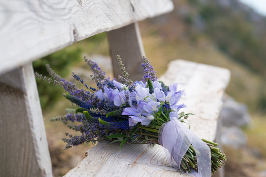 Fototapeta elegant wedding bouquet of purple flowers and herbs lies on the bench