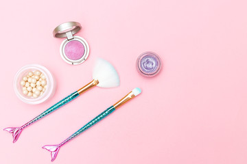 Makeup brush mermaid and eyeshadow on pink background.  Copy space