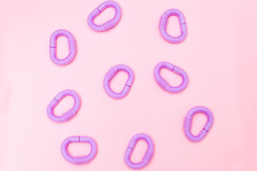 Fototapeta premium Violet hair curlers on pink background. Flat lay