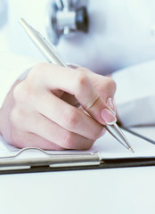Female medicine doctor hand holding silver pen writing something on clipboard closeup.