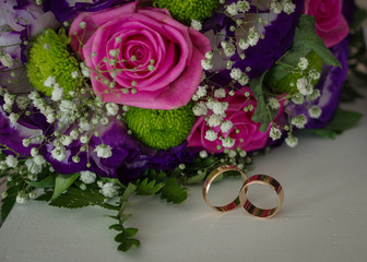 Wedding bouquet with wedding rings. Gold wedding rings lie near the bouquet for the bride. Wedding accessories