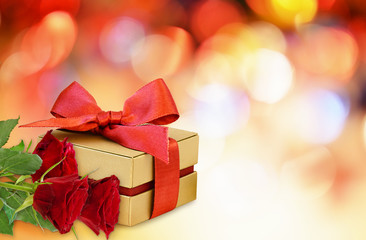 Gift box with red ribbon bow and red rose flowers