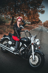 Fototapeta na wymiar Beautiful biker woman posing outdoor with motorcycle. Pin-up style. 