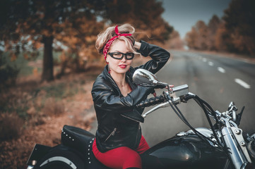 Fototapeta na wymiar Beautiful biker woman posing outdoor with motorcycle. Pin-up style. 