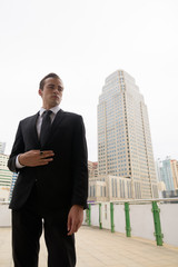 Portrait of young businessman wearing suit and standing in city