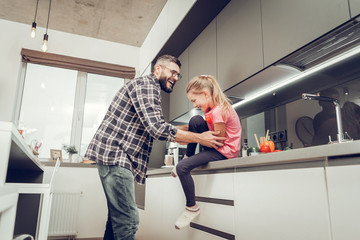Obraz premium Cute long-haired girl in a pink t-shirt having wonderful time with her father